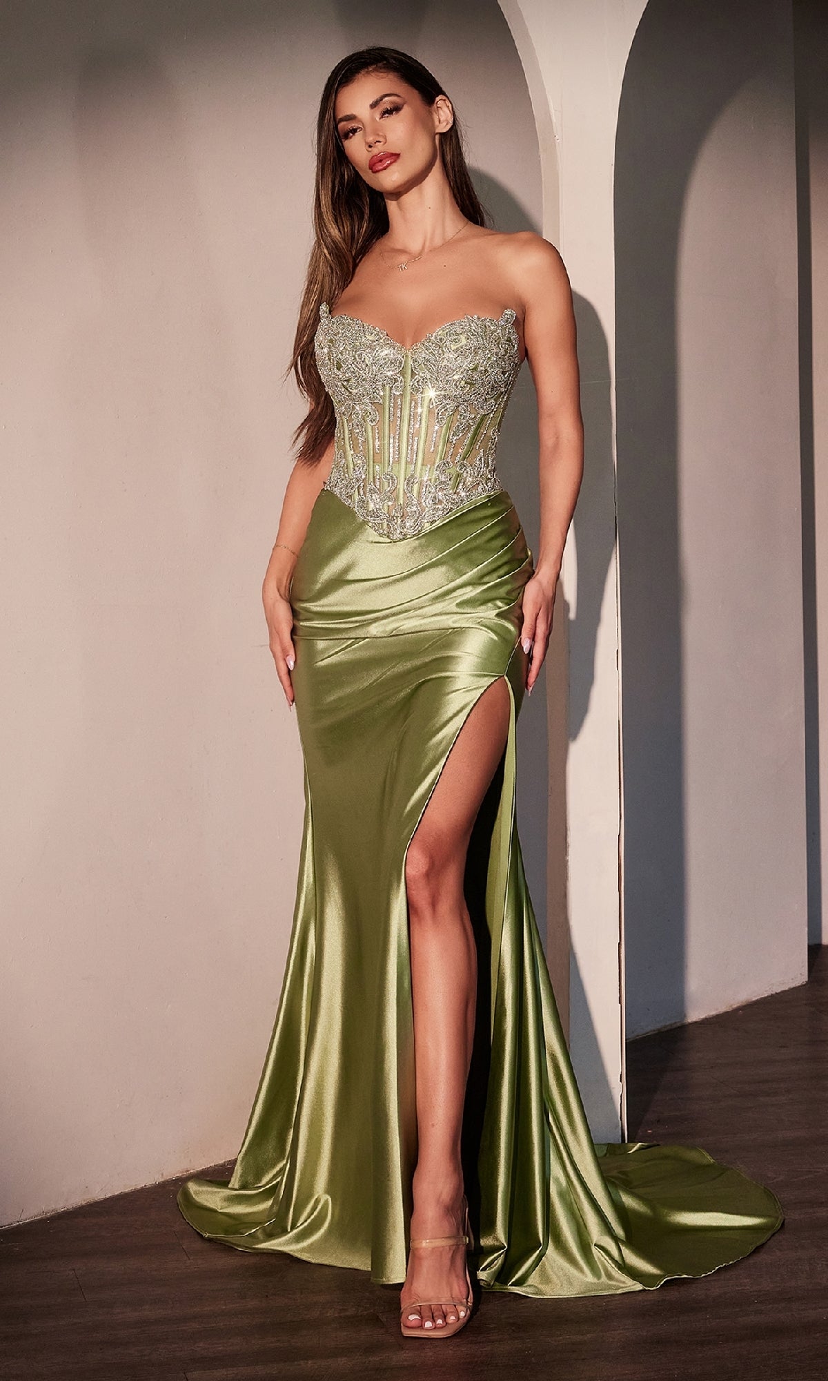 A woman poses indoors against an arched wall wearing the Strapless Long Corset Prom Dress: Ladivine CD736, featuring a beaded corset bodice and a high thigh slit.